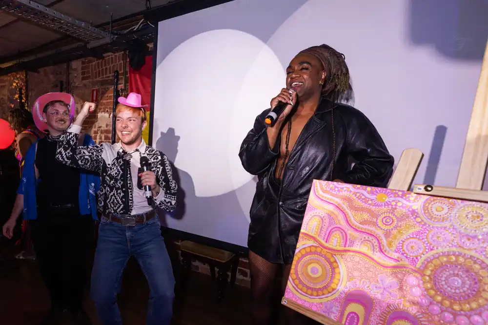 Zaachariaha Fielding on stage at Nungay night beside Rivah Jackson's painting- 'coming together.'